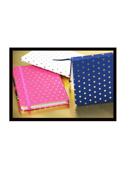 A5 notebooks with small gold dot covers shown in pink, blue, and white on a gold surface.