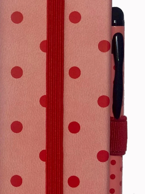 Close-up of A6 spotty notebook showing elastic side closure, pen loop, and dotted cover pattern