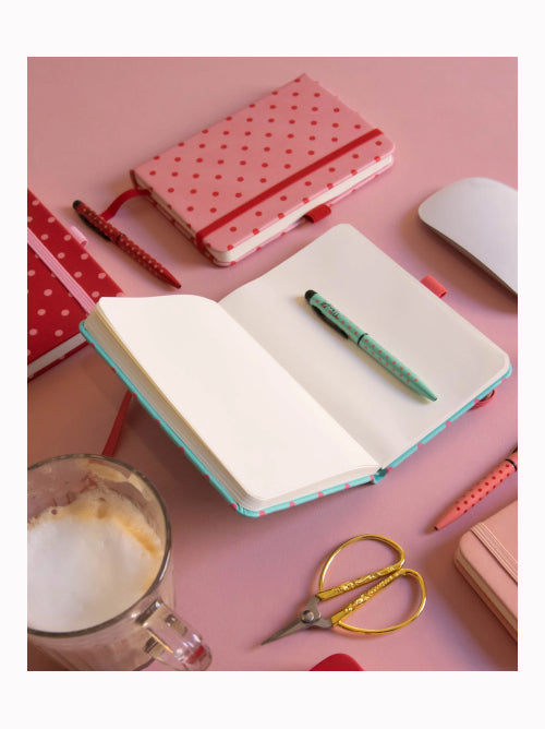 A6 spotty notebook opened to show plain white pages and ribbon bookmark