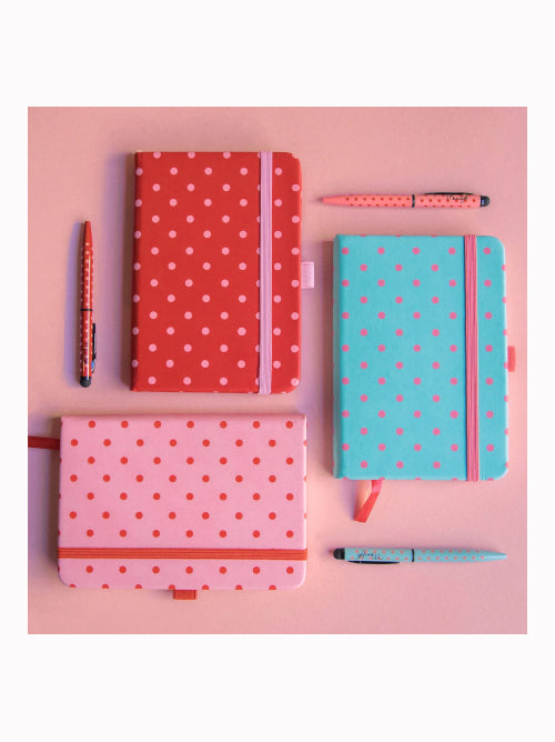 Aerial view of A6 spotty notebooks in different colours, each with a matching pen and elastic closure