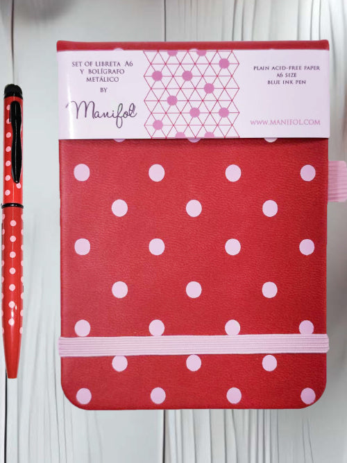 Pocket-sized spotty notebook with elastic closure and matching metallic pen beside the notebook