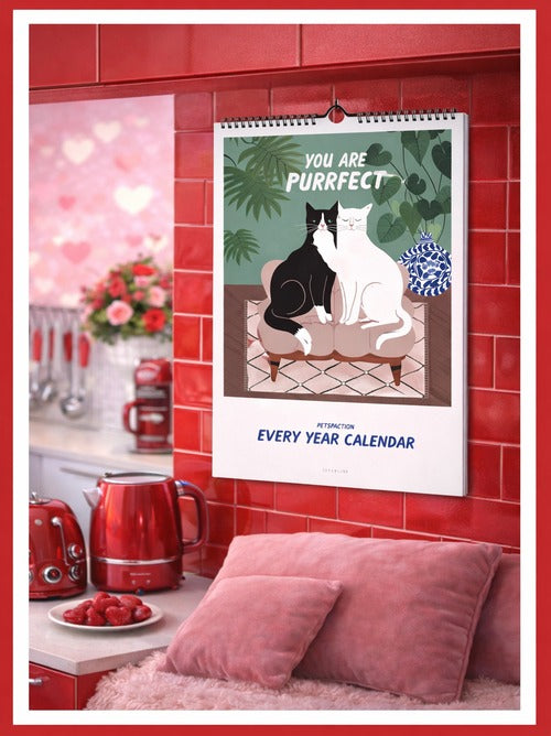 Illustrated wall calendar hanging on a red tiled wall with two cats and the text YOU ARE PURRFECT