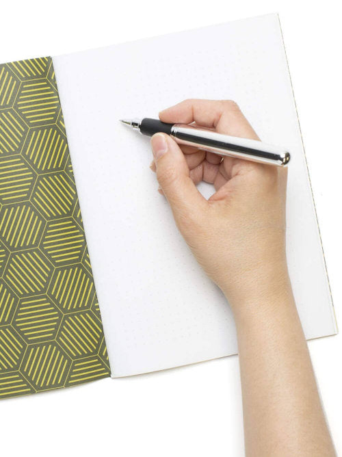 a hand writing on the paper inside the lime green notebook to show the inside cover that has a different design, also green and tessellating but different to the front cover. 