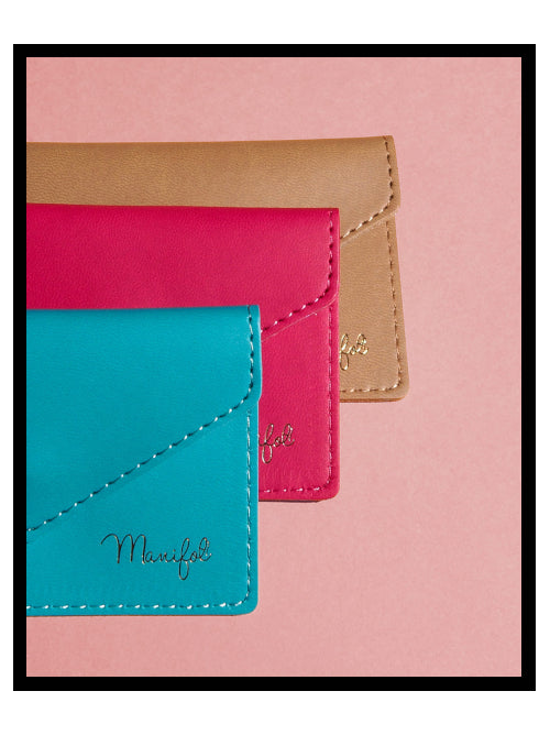 Stacked recycled vegan leather card wallets in teal, red and brown on a pink background.