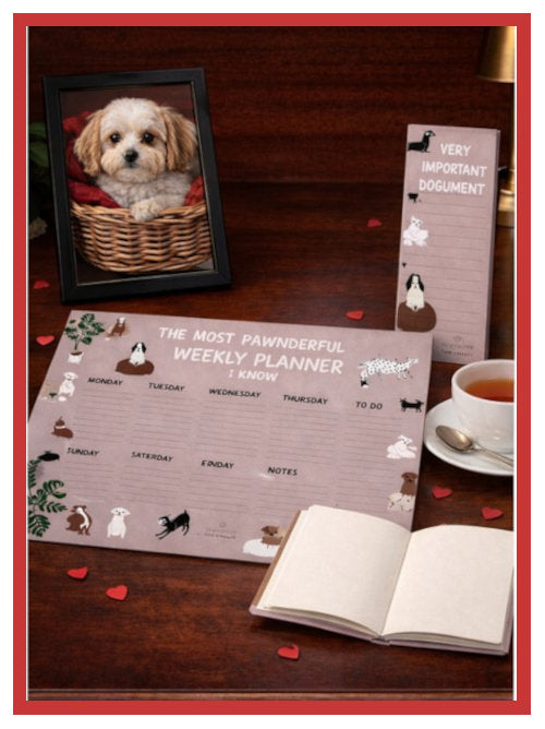 Stationery set including a planner, notebook and notepad arranged on a desk next to a framed dog photograph