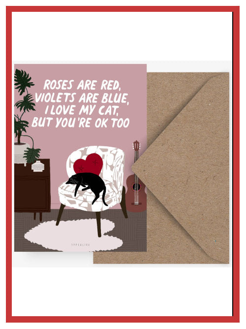 Funny Valentine postcard with sleeping black cat illustration reading “Roses are red, violets are blue, I love my cat but you’re OK too”, shown with kraft envelope
